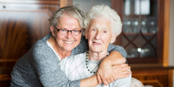 Adult daughter smiling and hugging her mom