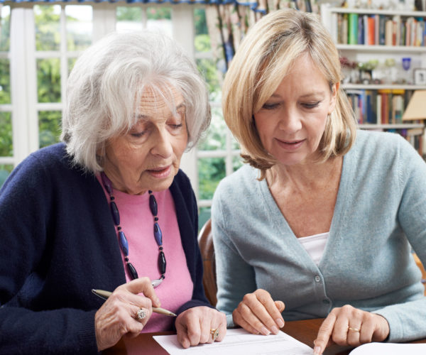 Adult daughter and mother signing a contract